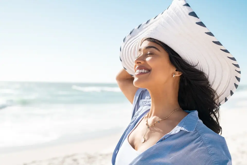 Woman enjoying a sunny beach day in a wide-brimmed hat