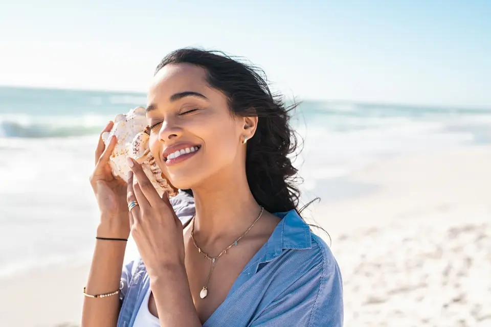 Woman smiling while holding a seashell